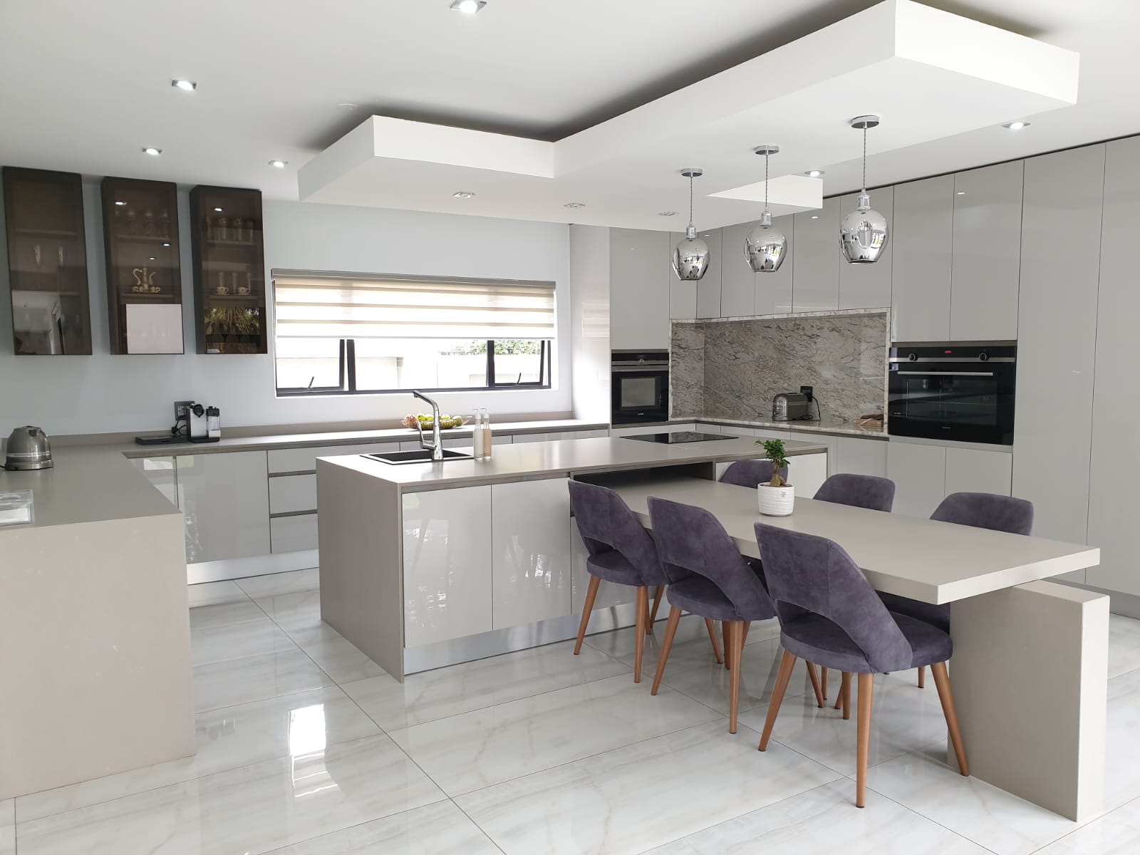 Contemporary minimal Pandors Designs kitchen in soft grey gloss cabinetry with a marble splashback