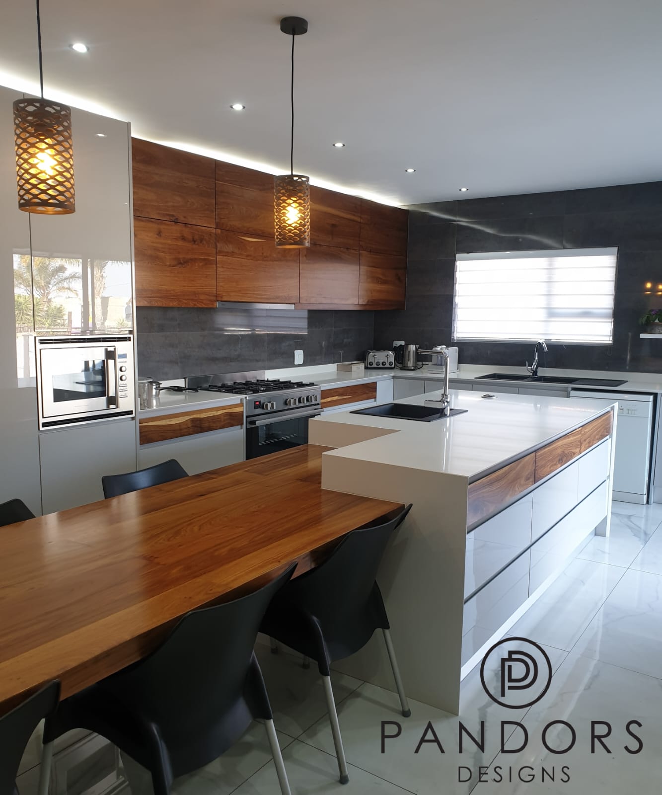 Warm timeless Pandors Designs kitchen with walnut cabinetry, white gloss island and a live-edge dining table