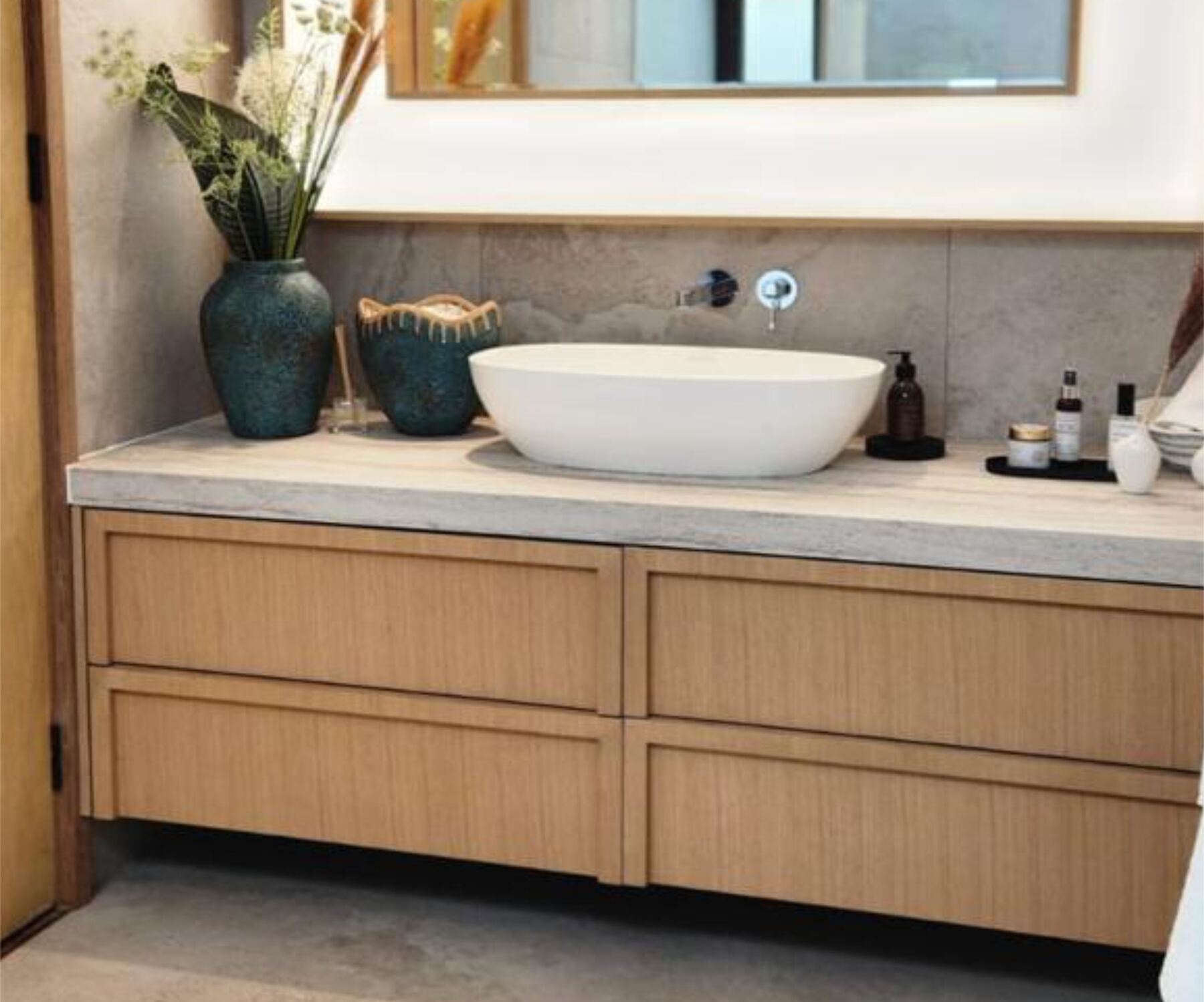 Warm detailed Pandors Designs vanity in oak cabinetry with a concrete-look countertop and ceramic decor