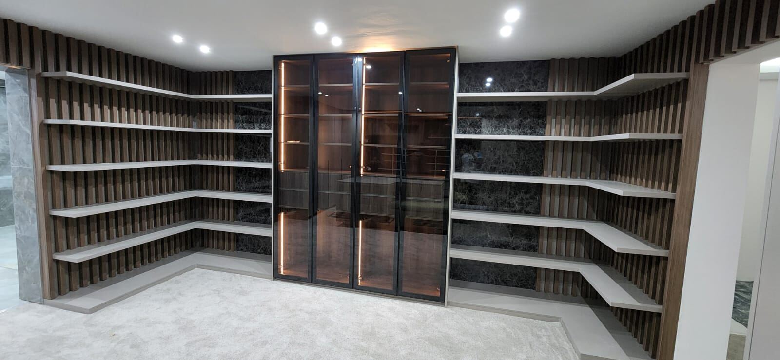 Curved Pandors Designs walk-in dressing room in slatted wood with a backlit glass display cabinet